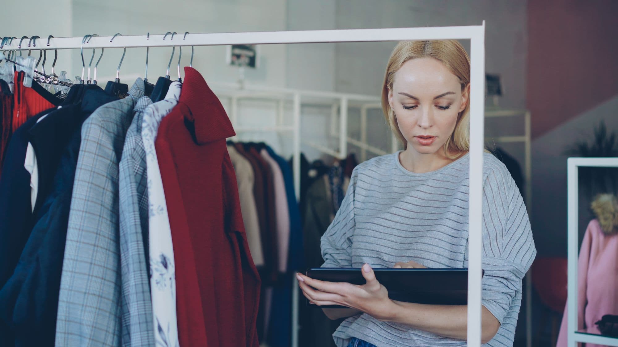 Retail operator checking clothing inventory on a tablet